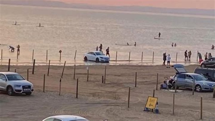 Moment frantic beachgoers try to rescue stranded cars from rising tide on beach at Weston-Super-Mare during heatwave